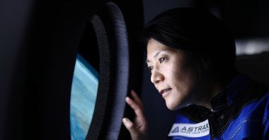 A commercial space traveler looking at the Earth through the window of a spaceship. (Getty Images Photo)