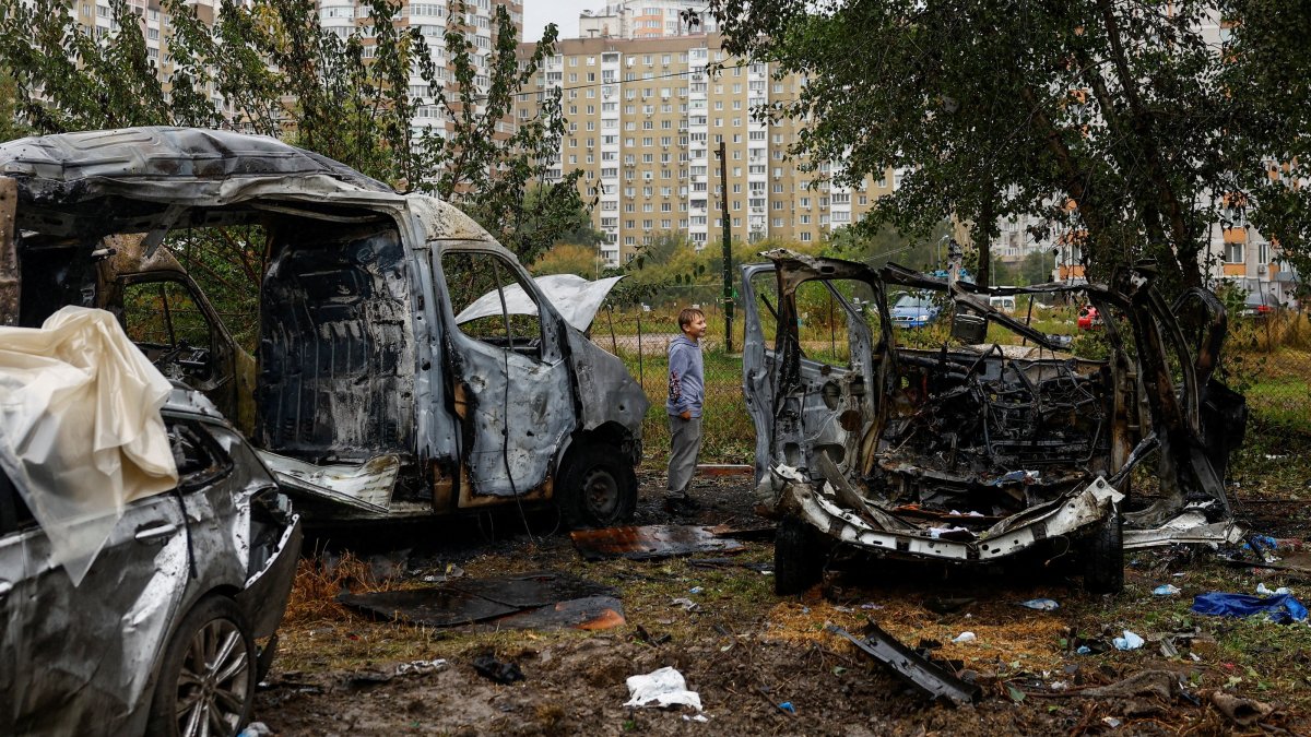 A boy stands next to vehicles hit by a Russian drone strike at a parking lot in a residential area, amid Russia's attack on Ukraine, in Kyiv, Ukraine, Sept. 24, 2026. (Reuters Photo)
