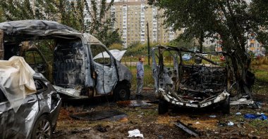 A boy stands next to vehicles hit by a Russian drone strike at a parking lot in a residential area, amid Russia's attack on Ukraine, in Kyiv, Ukraine, Sept. 24, 2026. (Reuters Photo)