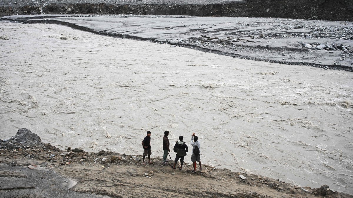 Men stand along a river in the aftermath of the Aug. 26 flash flood at Betrawoti Bazaar in Nuwakot district, Nepal, Sept. 26, 2026. (AFP Photo)