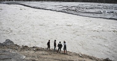 Men stand along a river in the aftermath of the Aug. 26 flash flood at Betrawoti Bazaar in Nuwakot district, Nepal, Sept. 26, 2026. (AFP Photo)