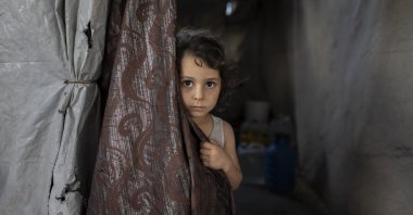 A child looks from behind curtain at a shelter for Gaza's war displaced people, Jabalya, Gaza, Sept. 26, 2026. (AA Photo)
