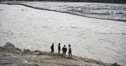 Men stand along a river in the aftermath of the Aug. 26 flash flood at Betrawoti Bazaar in Nuwakot district, Nepal, Sept. 26, 2026. (AFP Photo)