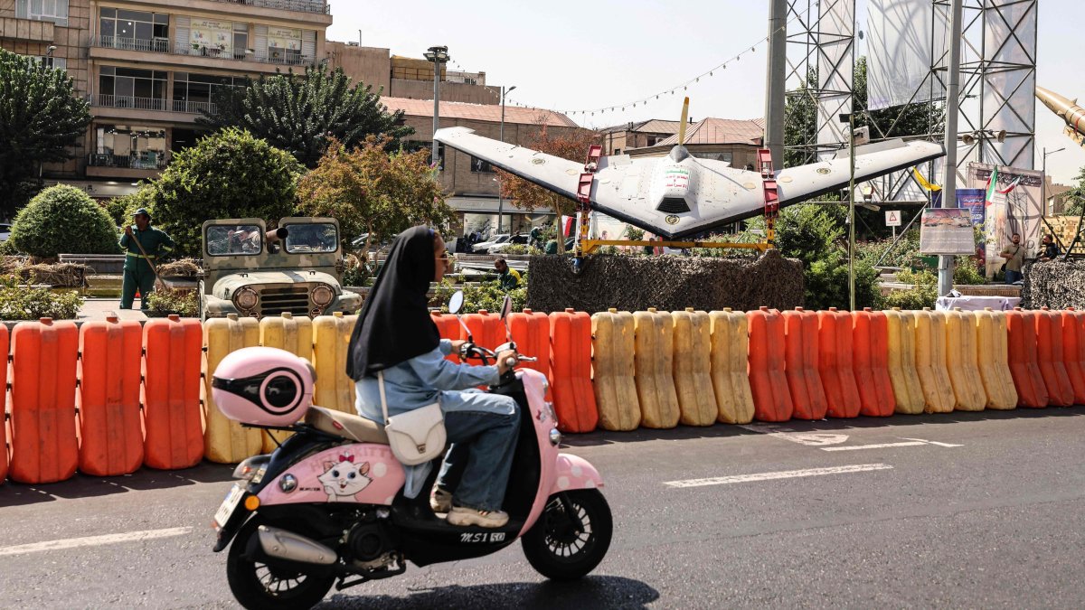 A woman rides a scooter past a military drone on display at Baharestan Square in Tehran, Iran, Sept. 28, 2026. (AFP Photo)