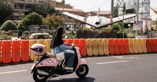 A woman rides a scooter past a military drone on display at Baharestan Square in Tehran, Iran, Sept. 28, 2026. (AFP Photo)