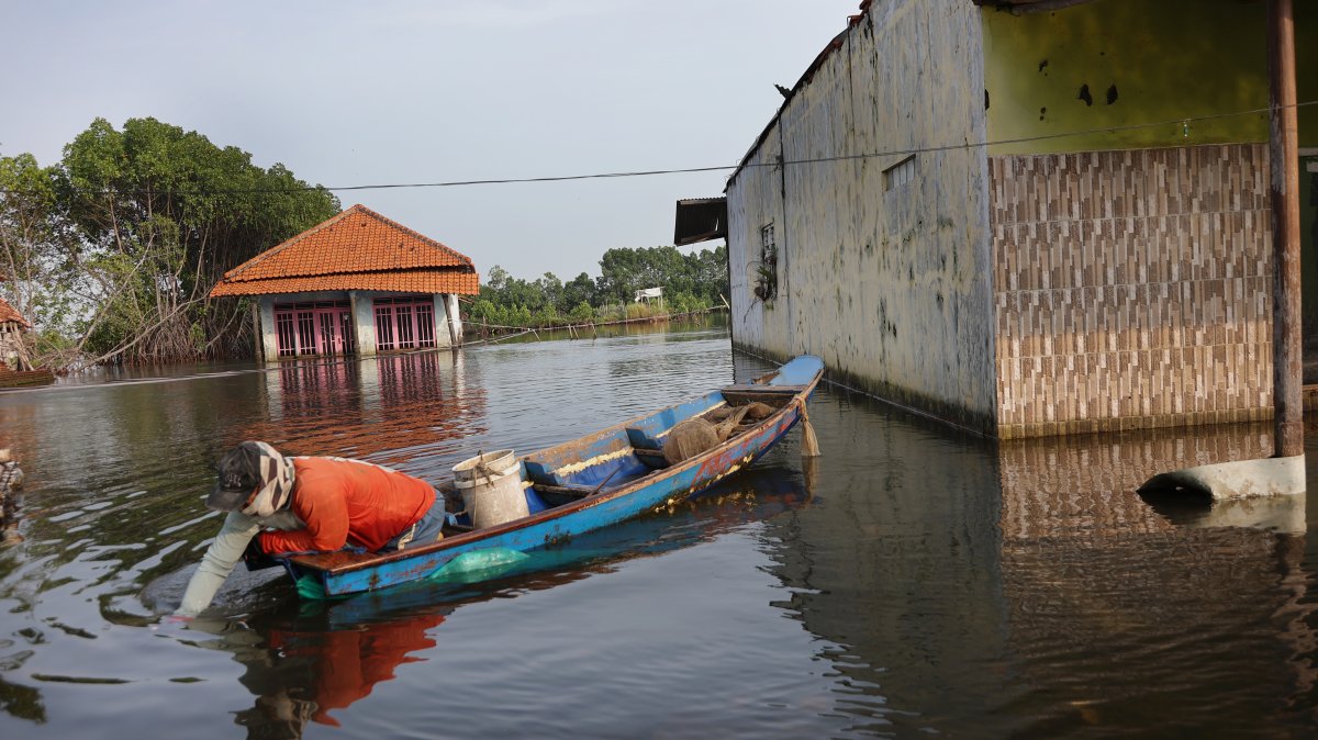 A fisherman navigates his boat near a residential house partially submerged by seawater in Pekalongan, Central Java, Indonesia, June 25, 2026. (Getty Images Photo)