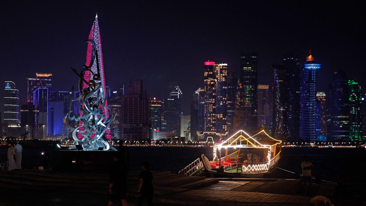 People walk along the Corniche Promenade facing the skyline of illuminated high-rise buildings in Doha, Qatar, Sept. 4, 2026. (AFP Photo)