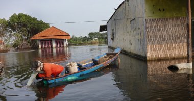 A fisherman navigates his boat near a residential house partially submerged by seawater in Pekalongan, Central Java, Indonesia, June 25, 2026. (Getty Images Photo)