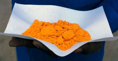 A man holds a dash of processed ore, called “yellowcake,” at the uranium mine in the Arlit region, Niger, 1990s. (Getty Images Photo)