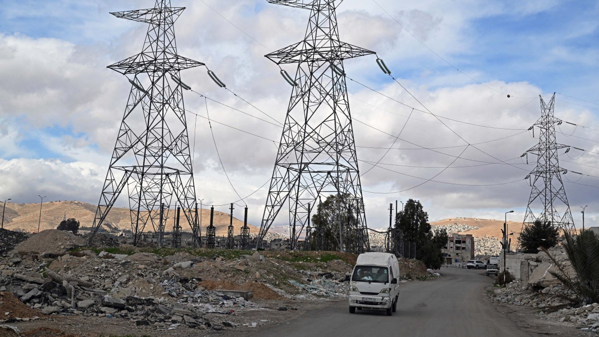 A van drives past electric pylons installed along a street near Damascus, Jan. 29, 2026. (AFP File Photo)
