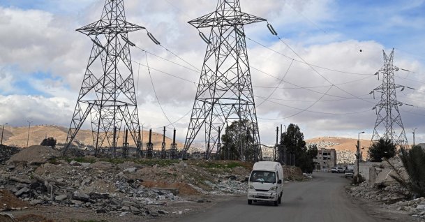 A van drives past electric pylons installed along a street near Damascus, Jan. 29, 2026. (AFP File Photo)