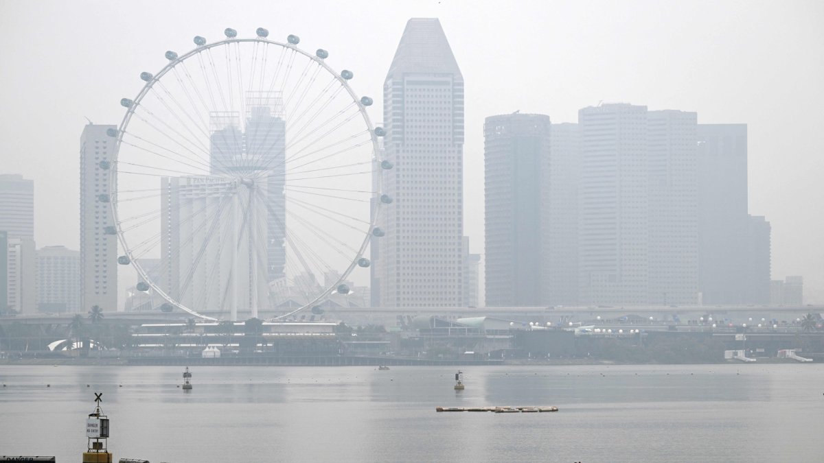 Workers sail along the Marina Reservoir as the city skyline is shrouded in haze, Singapore, Sept. 28, 2026. (AFP Photo)