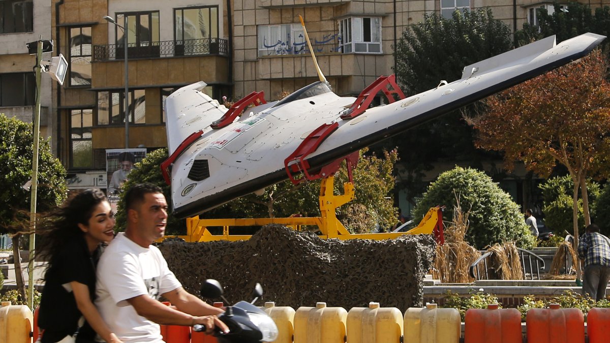 People ride a scooter past a military drone on display at Baharestan Square in Tehran, Iran, Oct. 1, 2026. (AA Photo)