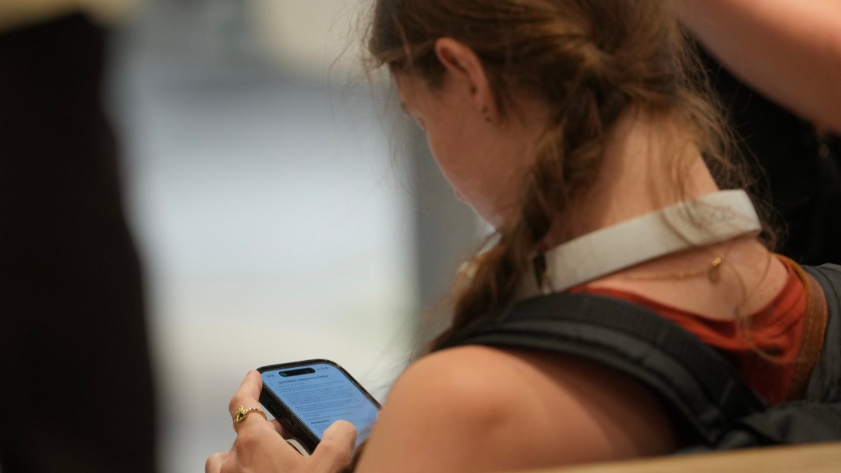 A teenager looks at her mobile phone in London, U.K., June 15, 2026. (AP Photo)