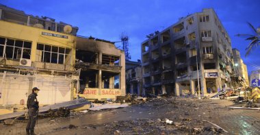 A police officer stands near damaged buildings on the street littered with debris from the explosions that killed 46 and injured about 50 others, Hatay, Türkiye, May 12, 2013. (AP Photo)