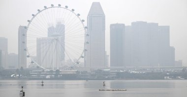 Workers sail along the Marina Reservoir as the city skyline is shrouded in haze, Singapore, Sept. 28, 2026. (AFP Photo)