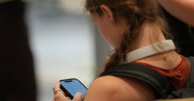 A teenager looks at her mobile phone in London, U.K., June 15, 2026. (AP Photo)