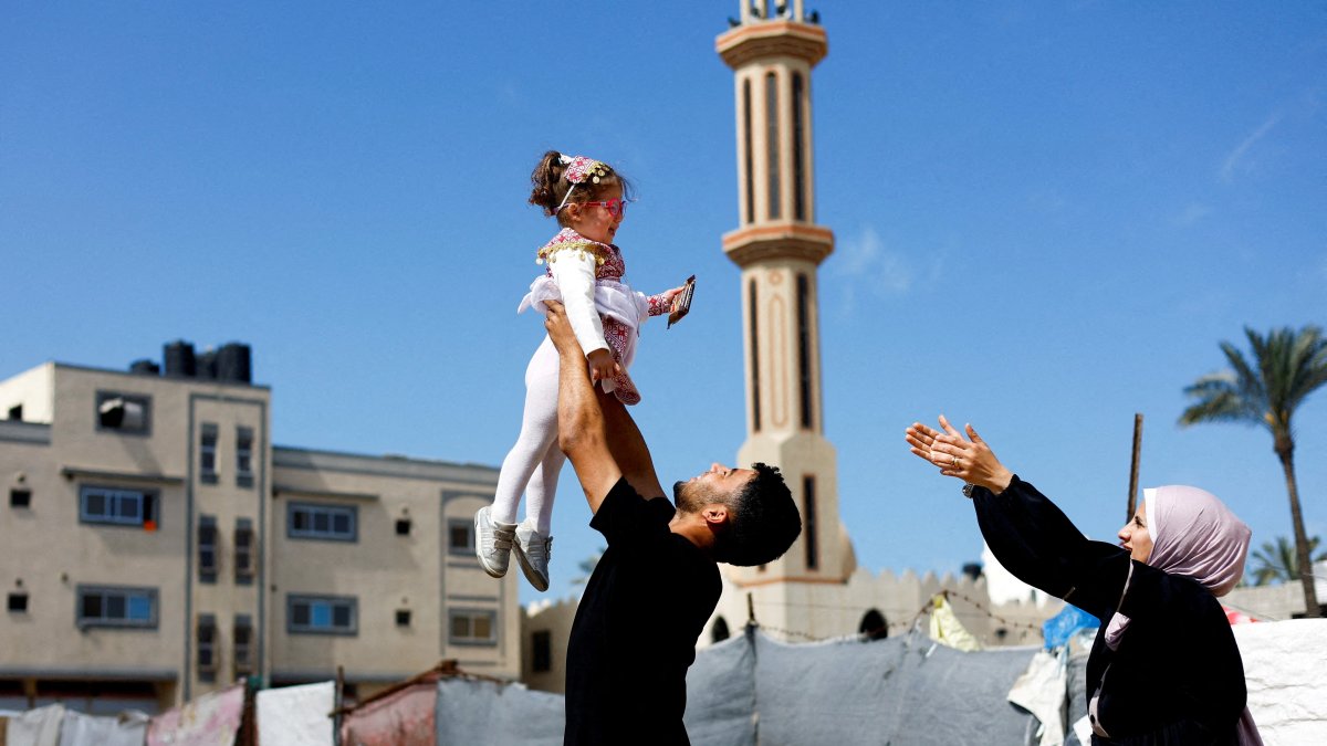 Maternal uncle of Bissan, who was evacuated as a premature baby during the two-year Israeli offensive for treatment in Egypt, plays with her after she returned to Gaza as her Palestinian mother Sundus al-Kurd, 29, reaches out her arms, Gaza Strip, Palestine, March 31, 2026. (Reuters Photo)