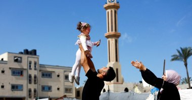 Maternal uncle of Bissan, who was evacuated as a premature baby during the two-year Israeli offensive for treatment in Egypt, plays with her after she returned to Gaza as her Palestinian mother Sundus al-Kurd, 29, reaches out her arms, Gaza Strip, Palestine, March 31, 2026. (Reuters Photo)