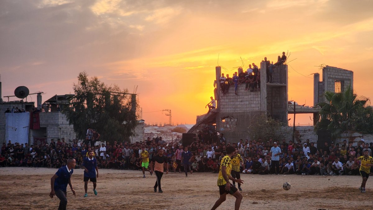 Palestinians gather around a makeshift football field, watching a match played in an open area amid tents and war-damaged buildings from Israeli attacks in Khan Younis, Gaza Strip, Palestine, Oct. 3, 2026. (AA Photo)