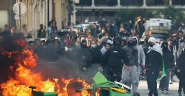 A student throws trash into a fire as protesting students carry out a blockade near Place de la Nation, Paris, France, Oct. 2, 2026. (AFP Photo)
