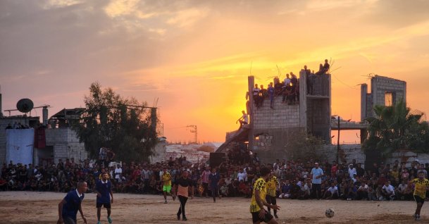 Palestinians gather around a makeshift football field, watching a match played in an open area amid tents and war-damaged buildings from Israeli attacks in Khan Younis, Gaza Strip, Palestine, Oct. 3, 2026. (AA Photo)