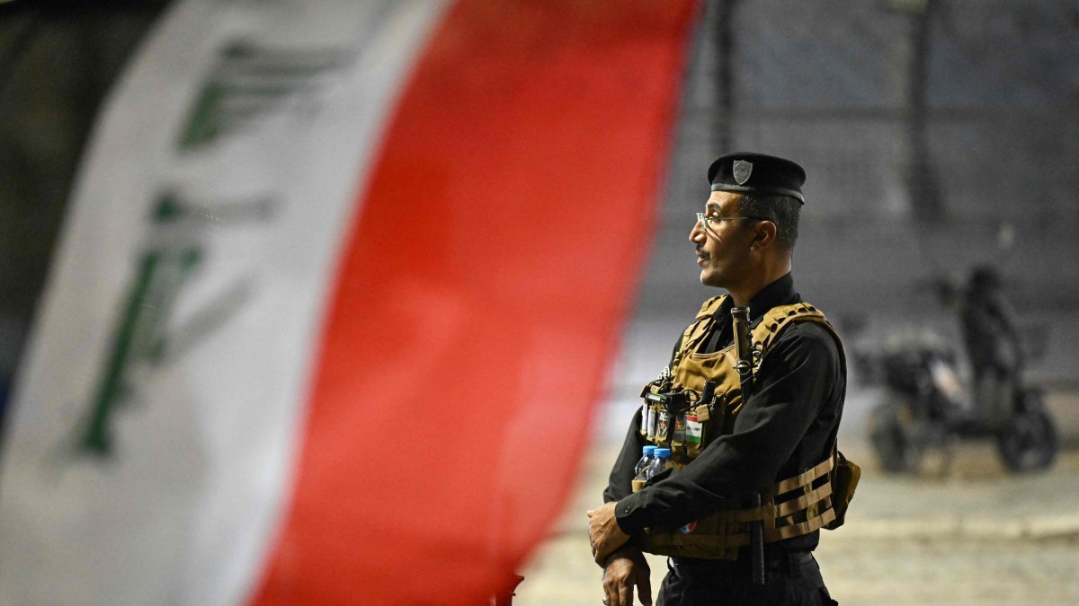 A security officer stands guard as people gather to celebrate Iraq National Day along the Shatt al-Arab Corniche, Basra, southern Iraq, Oct. 3, 2026. (AFP Photo)