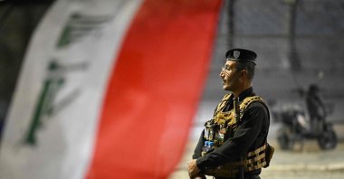 A security officer stands guard as people gather to celebrate Iraq National Day along the Shatt al-Arab Corniche, Basra, southern Iraq, Oct. 3, 2026. (AFP Photo)