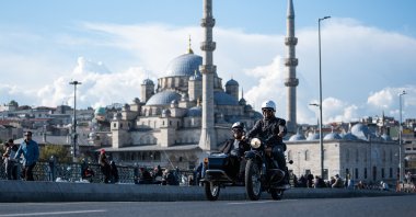 A man and a woman ride on a retro sidecar motorcycle in Eminönü with Yeni Camii in the background, Istanbul, Türkiye, Sept. 24, 2026. (AA Photo)