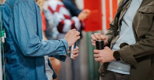 Teen students drinking energy drinks in school hallway. (Shutterstock Photo)