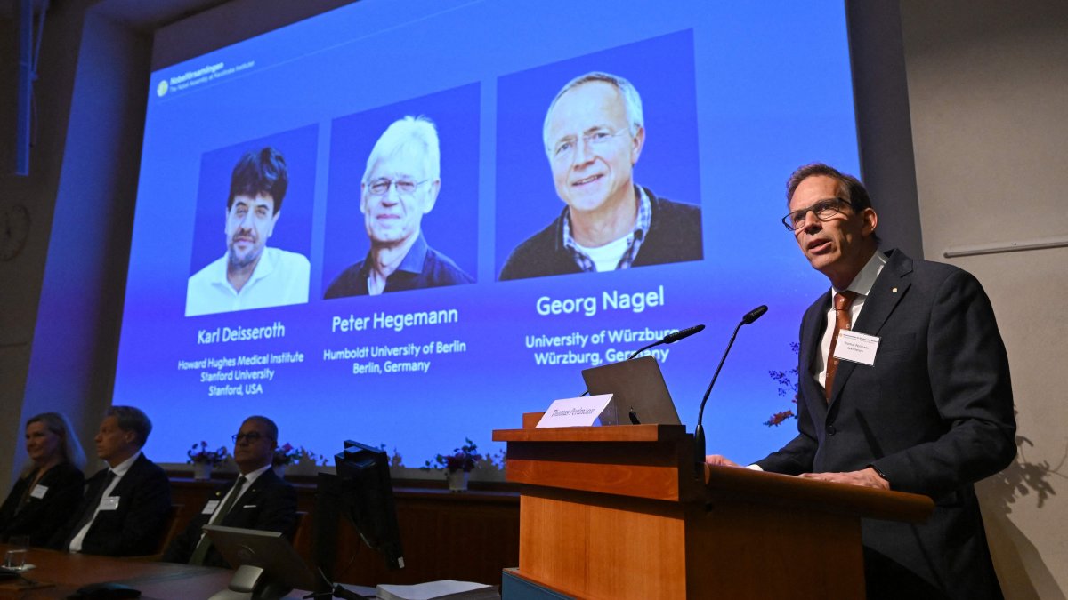 Nobel Committee Secretary-General Thomas Perlmann (R) speaks to the media in front of a screen displaying the names of this year's laureates (L-R) Karl Deisseroth, Peter Hegemann and Georg Nagel during the announcement of the 2026 Nobel Prize in Physiology or Medicine at the Karolinska Institute, Stockholm, Sweden, Oct. 5, 2026. (AFP Photo)