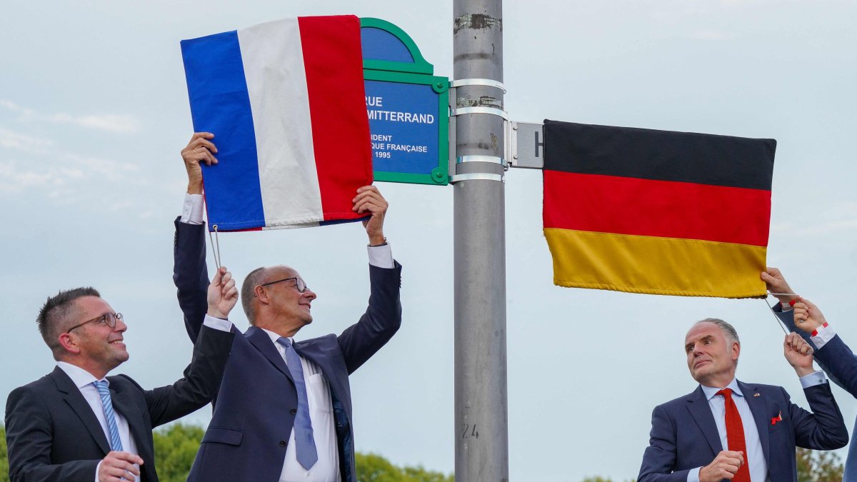 German Chancellor Friedrich Merz (C), Marc Speicher (L), Mayor of Saarlouis, and Jerome Spinoza (R), Consul General of France in Saarland, unveil the streets in honor of the late former German chancellor Helmut Kohl and the late former French president Francois Mitterrand, in Saarlouis, Germany, Sept. 28 2026. (AFP Photo)