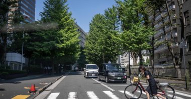 A woman crossing the street with her bike, Tokyo, Japan, Aug. 25, 2026. (AFP Photo)