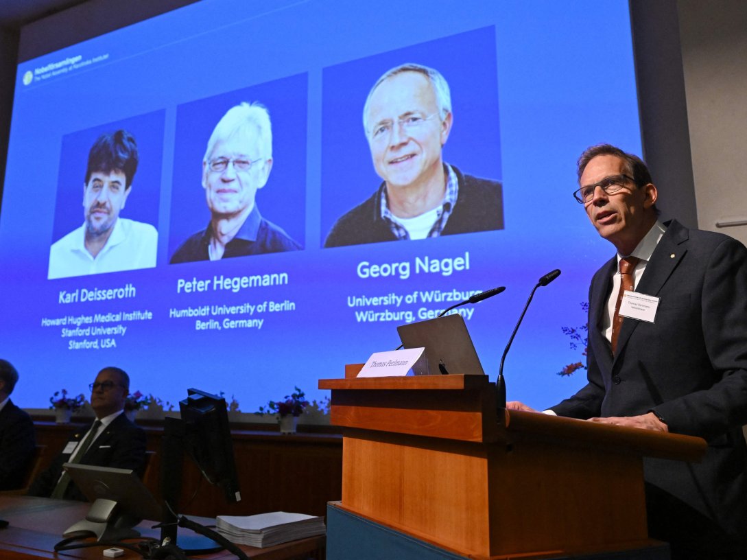 Nobel Committee Secretary-General Thomas Perlmann (R) speaks to the media in front of a screen displaying the names of this year's laureates (L-R) Karl Deisseroth, Peter Hegemann and Georg Nagel during the announcement of the 2026 Nobel Prize in Physiology or Medicine at the Karolinska Institute, Stockholm, Sweden, Oct. 5, 2026. (AFP Photo)