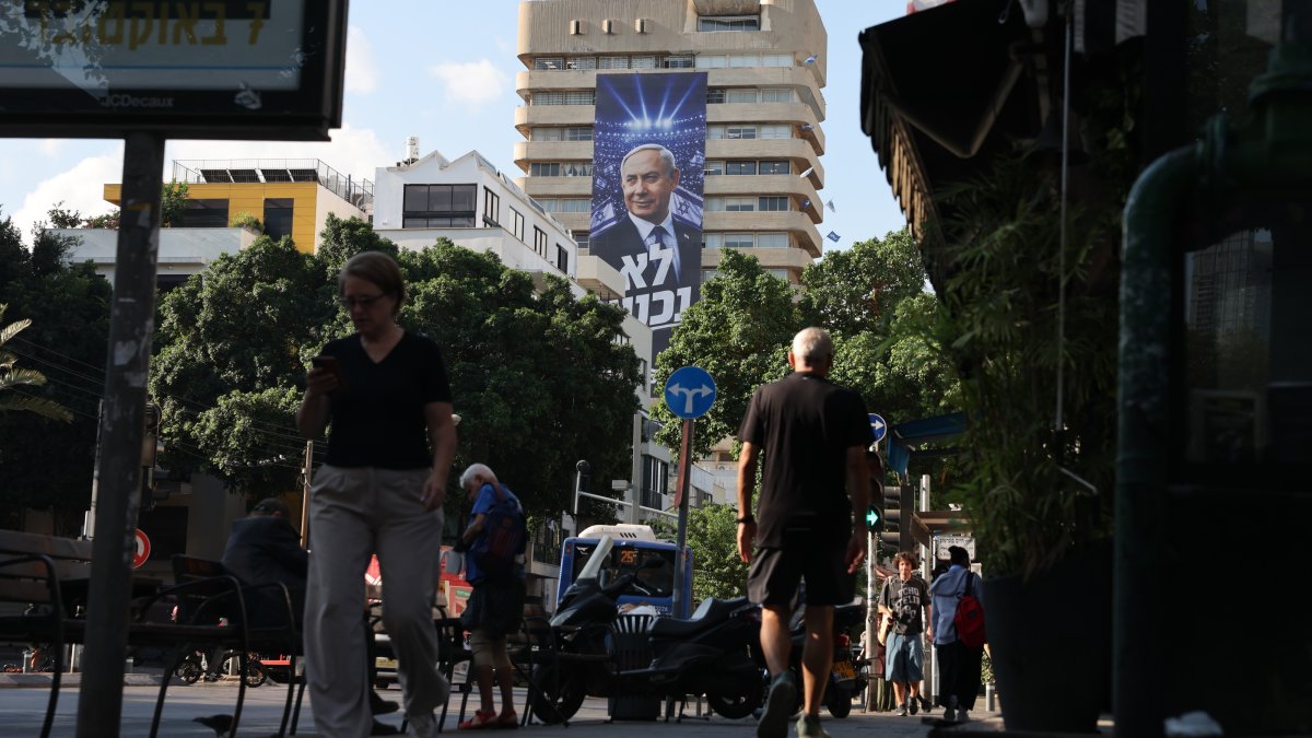 People walk past an election billboard showing Israeli Prime Minister Benjamin Netanyahu with the Hebrew phrase 'We will not surrender' in Tel Aviv, Israel, Oct. 6, 2026. (EPA Photo)