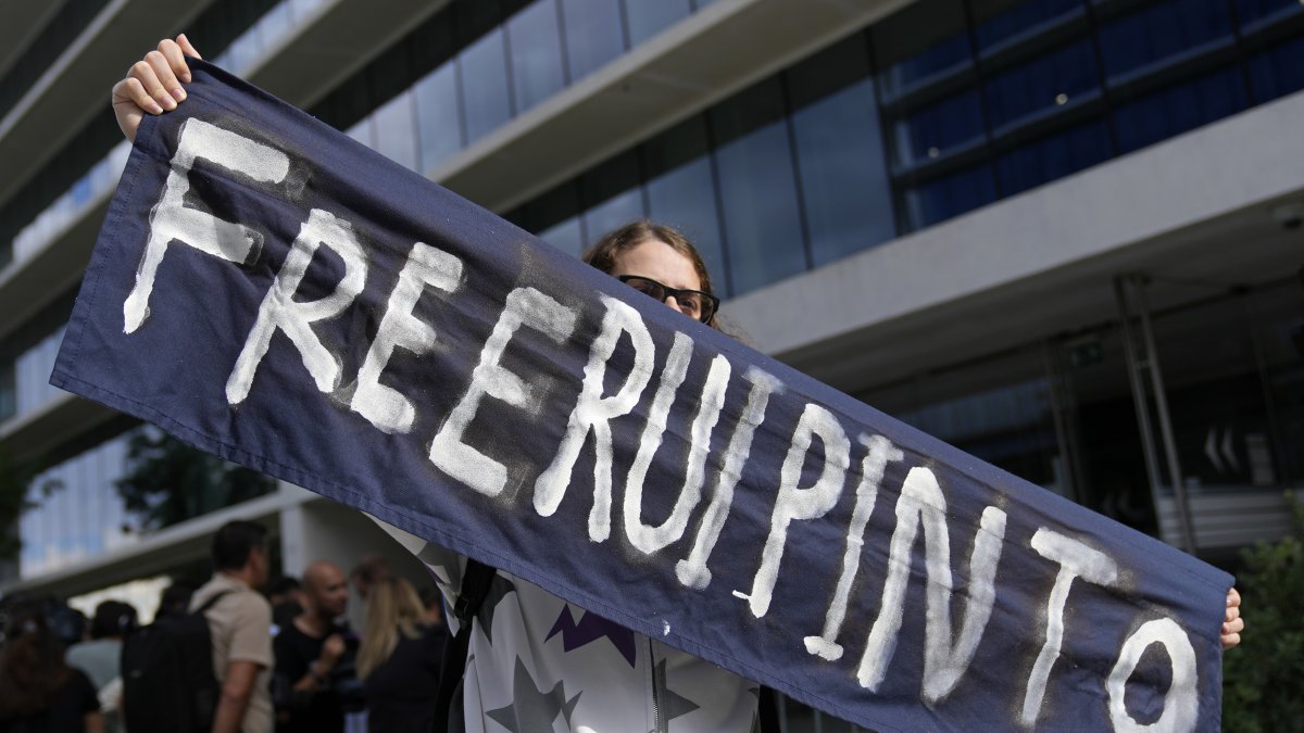 A supporter of Rui Pinto holds a banner outside the court where the Portuguese hacker, whose bombshell revelations on the "Football Leaks" website rocked European football, was convicted at the end of a three-year trial, Lisbon, Portugal, Sept. 11, 2023. (AP Photo)