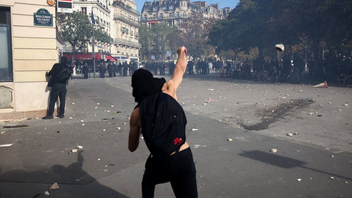 A protester throws stones amid clashes with French riot police during a demonstration by high school and university students, supported by teachers' union and school parents, in Paris, France, Oct. 6, 2026. (Reuters Photo)