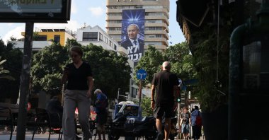 People walk past an election billboard showing Israeli Prime Minister Benjamin Netanyahu with the Hebrew phrase 'We will not surrender' in Tel Aviv, Israel, Oct. 6, 2026. (EPA Photo)