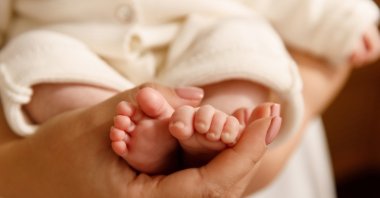 A mother’s hands cradle her newborn’s feet. (Shutterstock Photo)