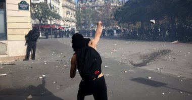 A protester throws stones amid clashes with French riot police during a demonstration by high school and university students, supported by teachers' union and school parents, in Paris, France, Oct. 6, 2026. (Reuters Photo)