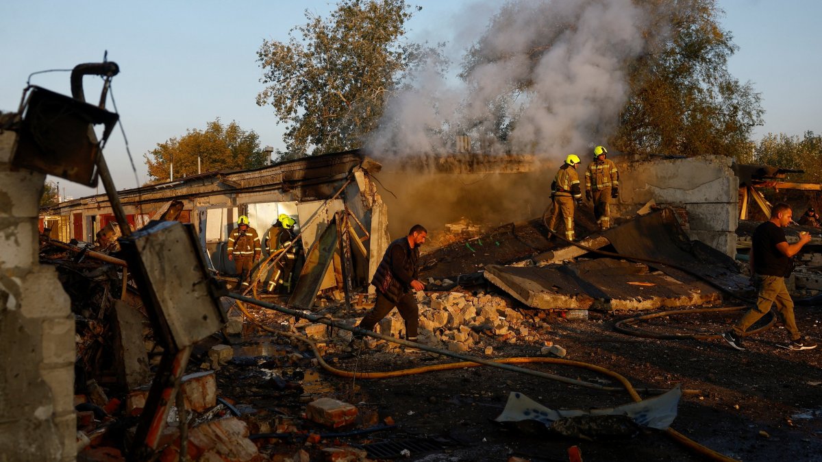 Firefighters work while residents walk past the site of private car garages hit by a Russian missile strike, in Kyiv, Ukraine, Oct. 7, 2026. (Reuters Photo)
