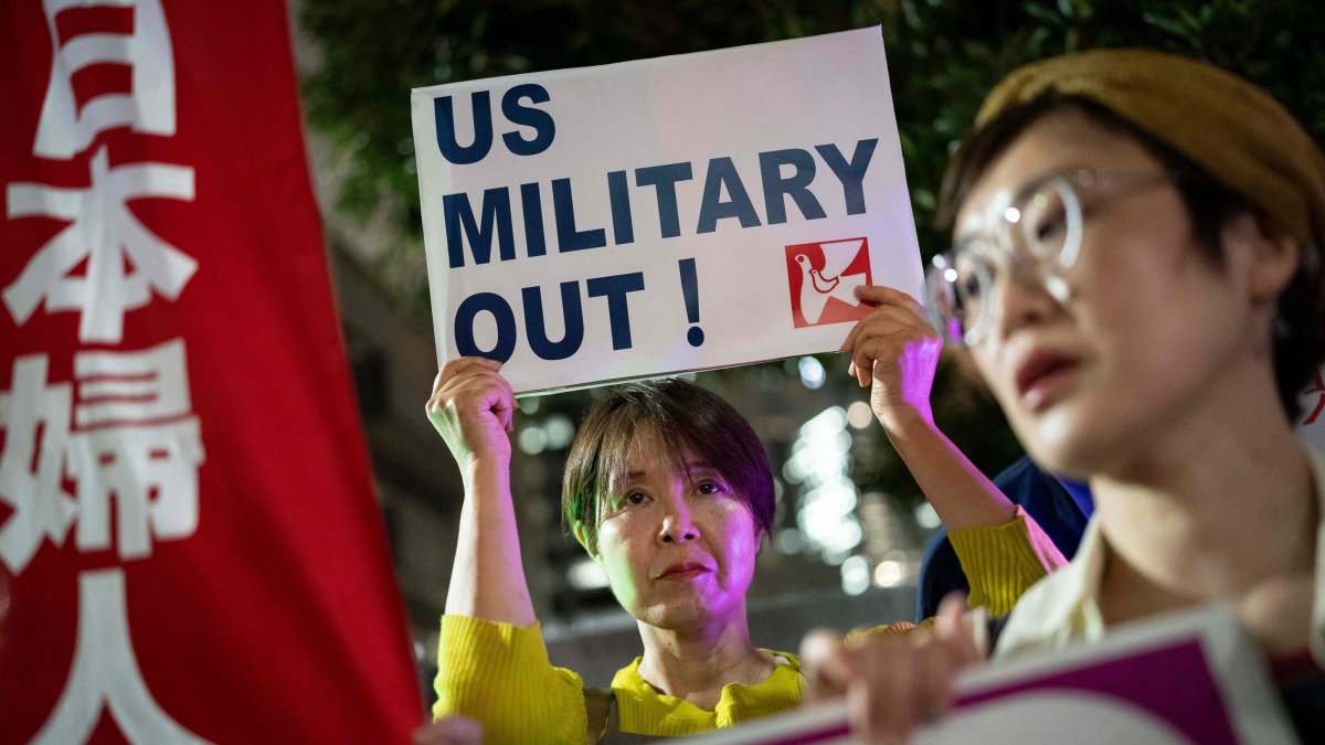 A woman holds up a placard reading 'US military out' during a protest against the killing of a woman in Okinawa allegedly committed by a U.S. Marine Corps member, Tokyo, Japan, October 5, 2026. (AFP Photo)