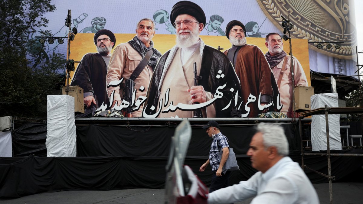 A man walks past a billboard depicting Iran's late Supreme Leader Ayatollah Ali Khamenei, the late former Hezbollah leader Hassan Nasrallah and the late military commander Qassem Soleimani, on a street in Tehran, Iran, Oct. 6, 2026. (Reuters Photo via Handout)