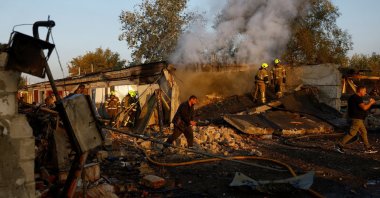 Firefighters work while residents walk past the site of private car garages hit by a Russian missile strike, in Kyiv, Ukraine, Oct. 7, 2026. (Reuters Photo)