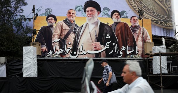 A man walks past a billboard depicting Iran's late Supreme Leader Ayatollah Ali Khamenei, the late former Hezbollah leader Hassan Nasrallah and the late military commander Qassem Soleimani, on a street in Tehran, Iran, Oct. 6, 2026. (Reuters Photo via Handout)