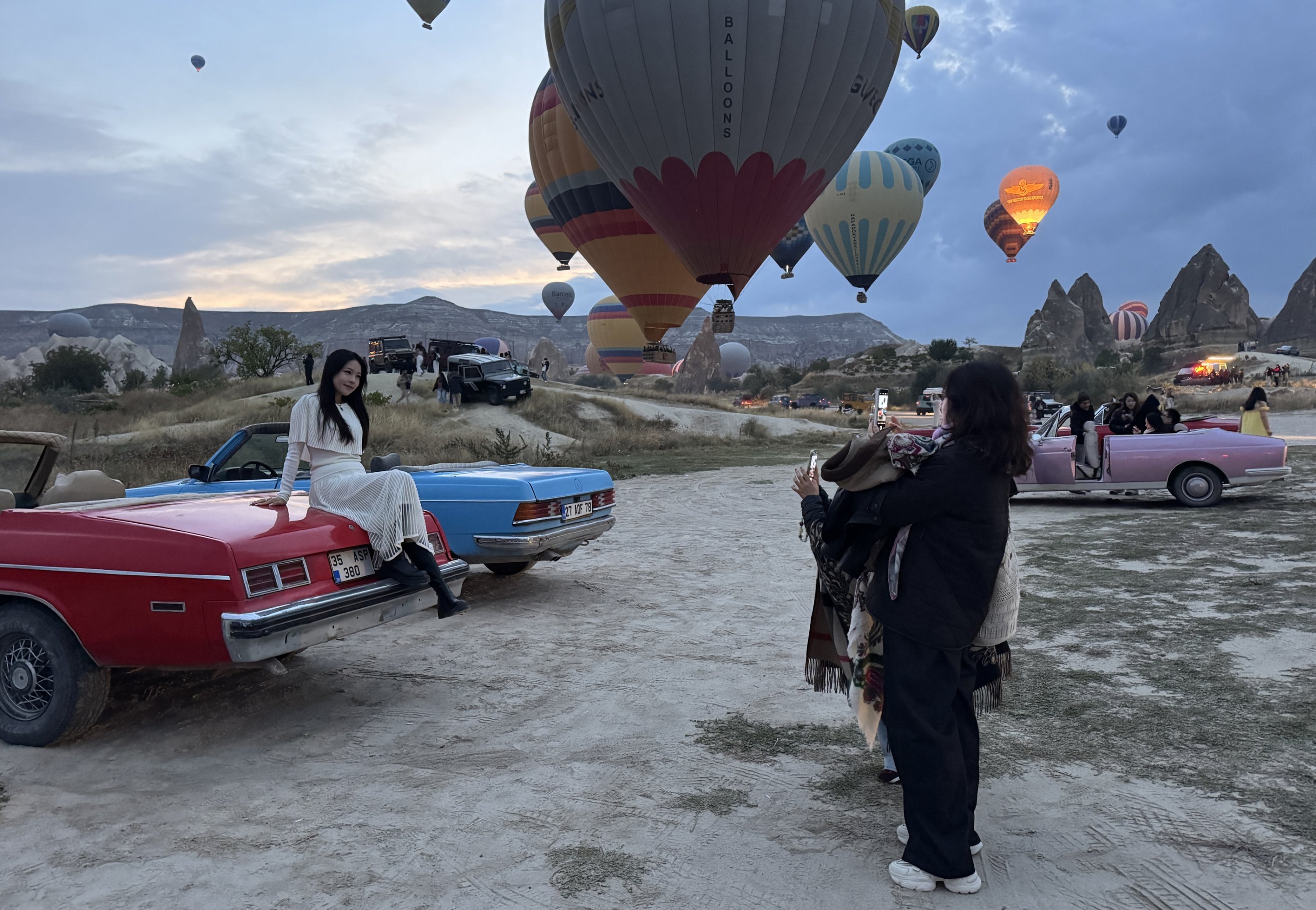 Visitors take photos as hot air balloons rise over Cappadocia, central Türkiye, Oct. 6, 2026. (AA Photo)