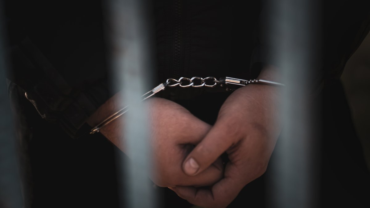 A handcuffed prisoner is pictured inside a prison cell. (Shutterstcok Photo)