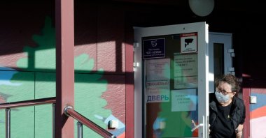 A security person wearing a face mask looks out from the door of an infectious diseases hospital in the town of Shelekhov, where an employee of the Irkutsk Antiplague Research Institute had died, Irkutsk region, Russia, Oct. 7, 2026. (AFP Photo)
