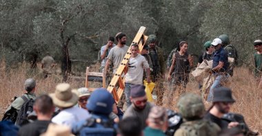 Israeli settlers, under the protection of Israeli forces, attack Palestinian farmers harvesting olives and foreign activists supporting them in the village of Deir Ibzi, near Ramallah, West Bank, Oct. 9, 2026. (AA Photo)