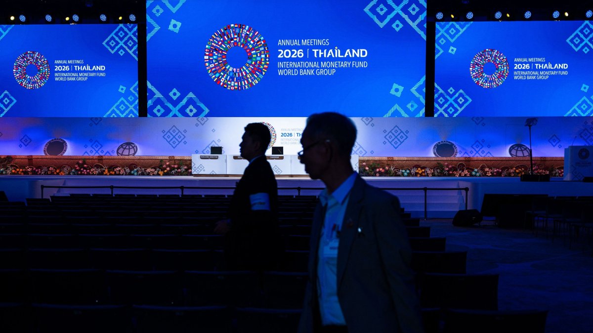 People stand in front of a display featuring the logo of the IMF-World Bank Group Annual Meetings 2026 during preparations for the event at the Queen Sirikit National Convention Center, Bangkok, Thailand, Oct. 9, 2026. (AFP Photo)